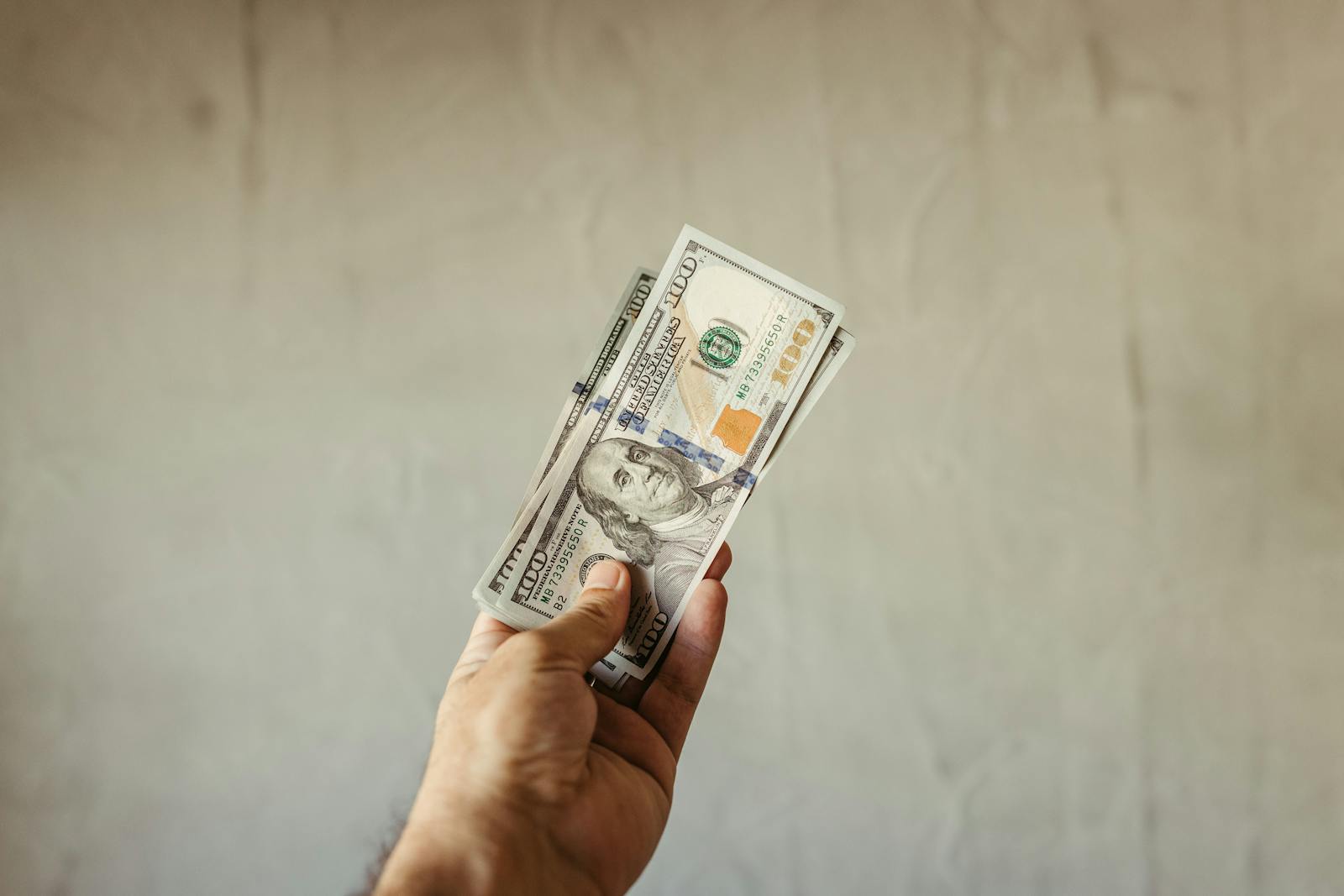 A hand holding a stack of US dollars symbolizing Financial freedom.