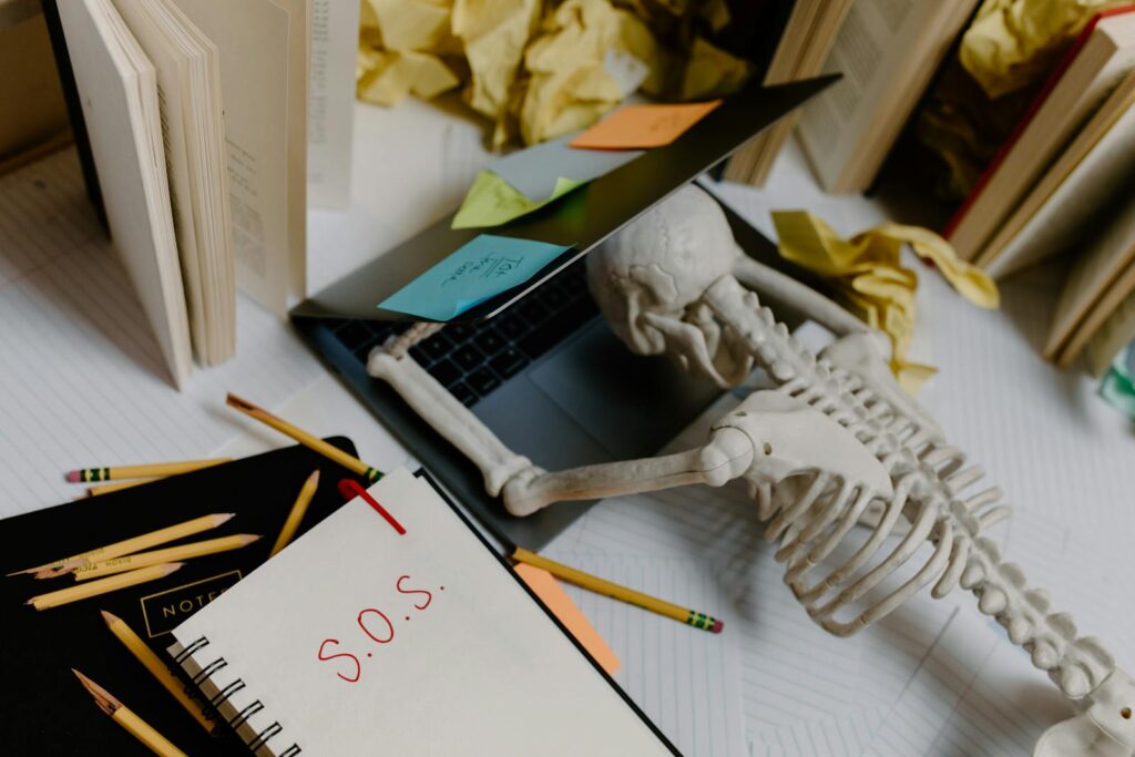 picture of skeleton overwhelmed at an untidy office desk with S.O.S. note signaling help for a clutter-free life.