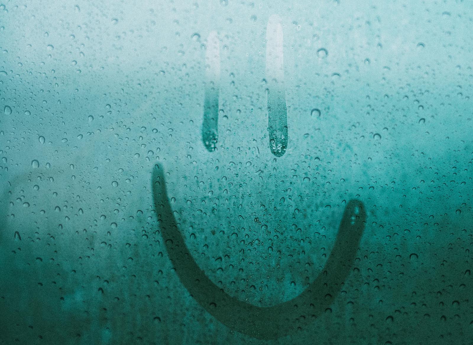 A smiley face drawn on glass expressing Happiness.